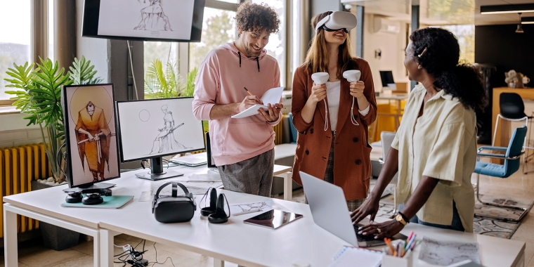 Group of gaming VR developers testing their new software in the office together.